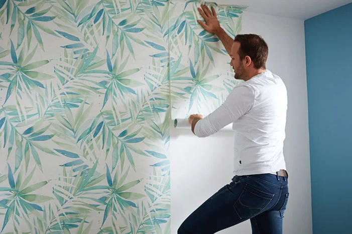 Person bringt Tapete mit Muster an